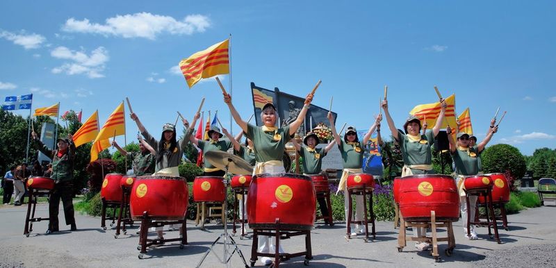 Đoàn biểu diễn trống ngoài trời, tay giơ cao dùi trống