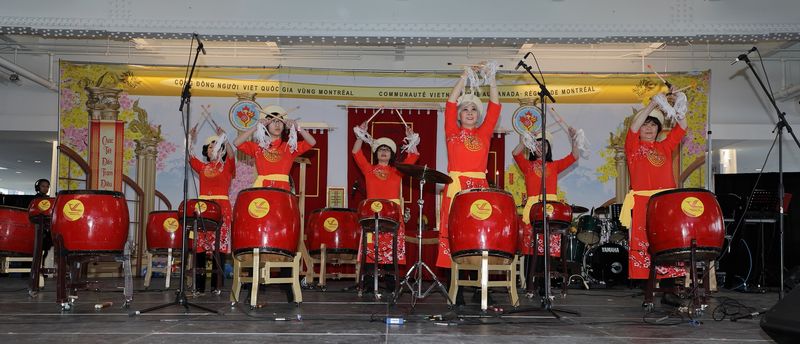 Các thành viên mặc áo dài đỏ biểu diễn trống trong chương trình Tết